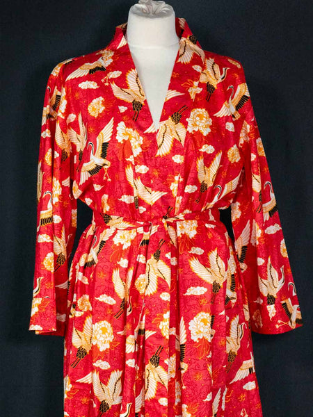 Red robe with bird pattern on a mannequin against a black background