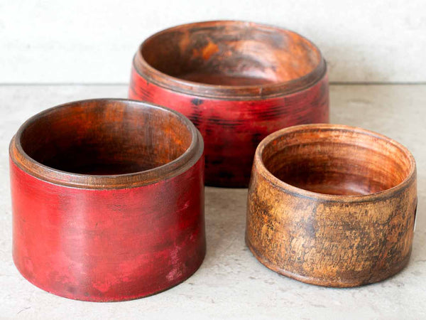 Three wooden bowls with a red interior on a light surface