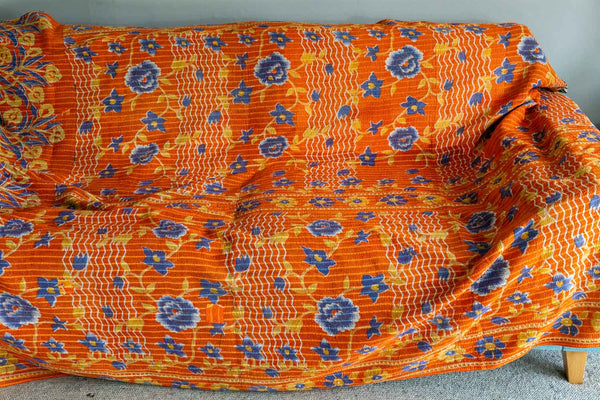 Orange fabric with blue floral patterns draped over a chair.