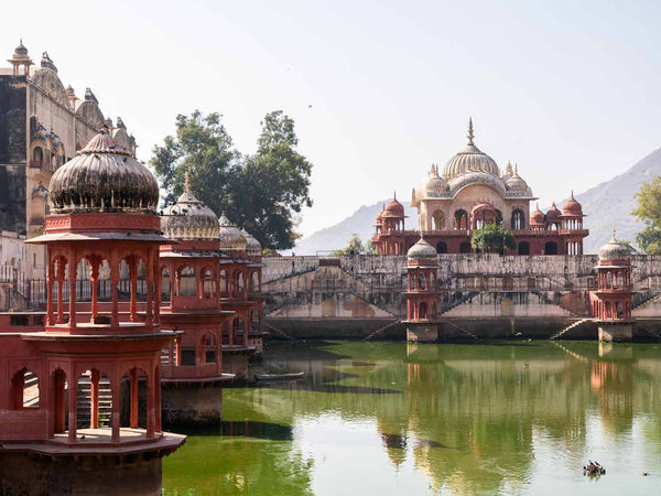 Traditional Indian architecture with domes and minarets near a body of water.
