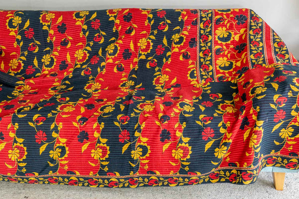 Furniture cover with red, yellow, and black floral pattern on a plain background