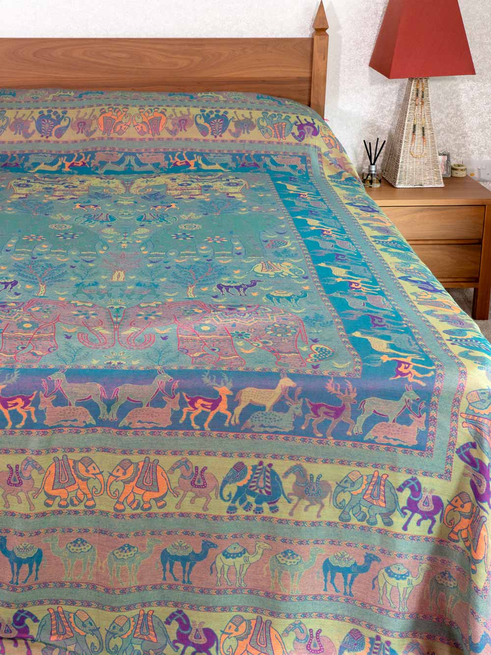 Colorful bedspread with animal patterns on a bed in a bedroom setting.