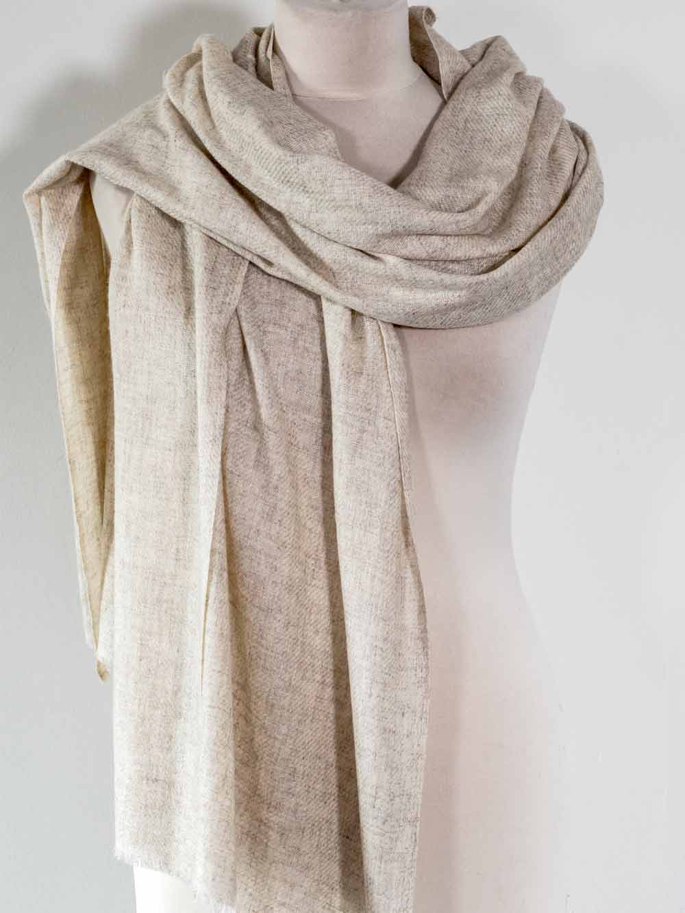 Beige scarf draped around a mannequin on a plain background