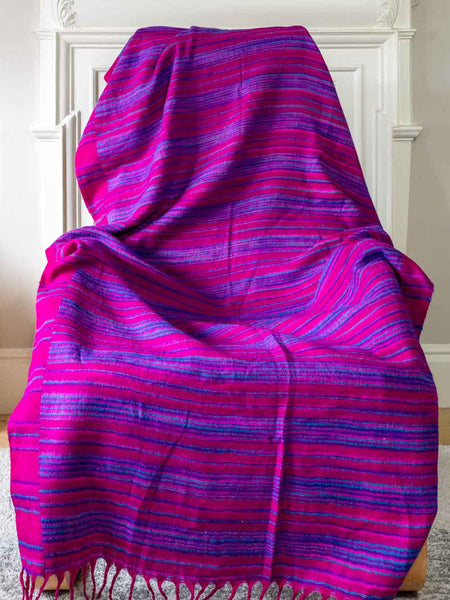 Pink and purple striped fabric draped over a chair against a white wall.