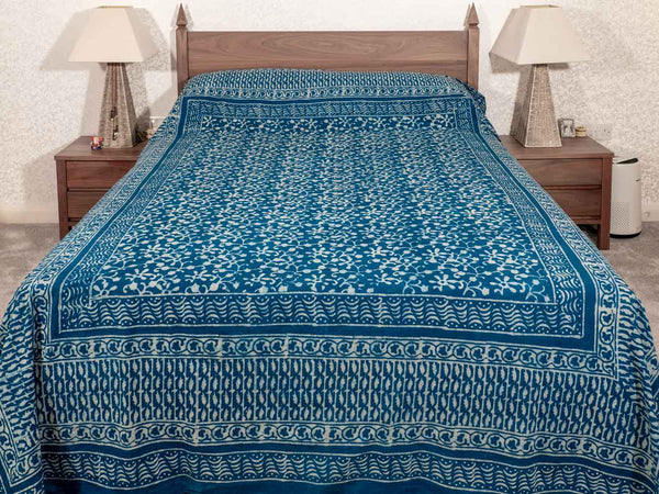 Blue and white patterned bedspread on a wooden bed in a bedroom setting.