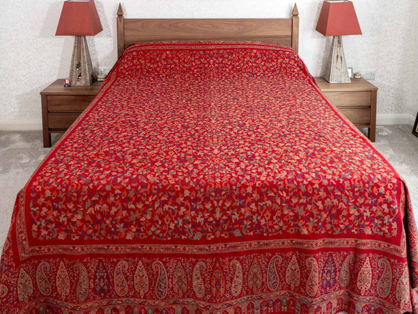 Red patterned bedspread on a wooden bed with matching nightstands and lamps.