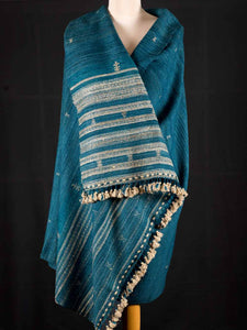 Blue shawl with white patterns draped over a mannequin against a black background