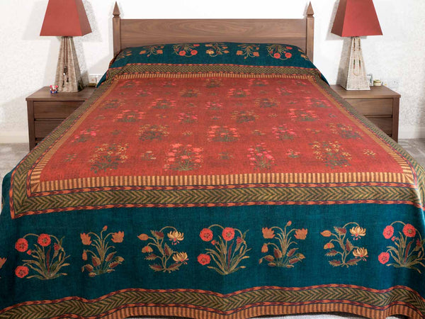 A traditional patterned bedspread with a red center and a dark teal border,