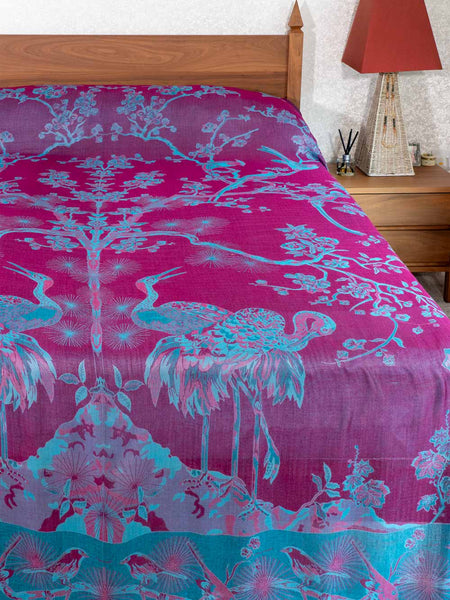 Bedspread with pink and blue floral and bird pattern on a bed