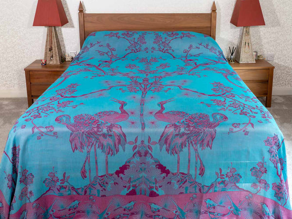 Bed with a blue and pink floral and bird patterned bedspread 