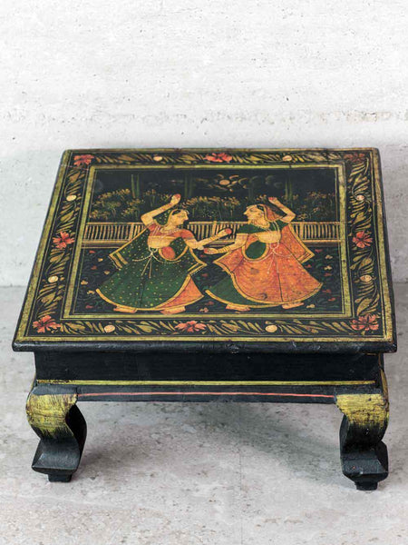 Decorative table with painted design of two women dancing on a white background
