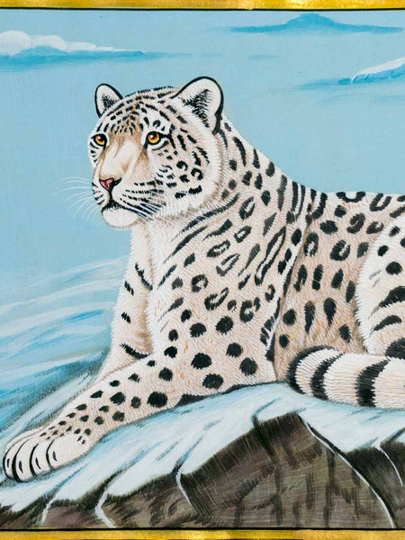 A detailed painting of a snow leopard resting on a snowy rock, set against a light blue icy background with gold borders at the top and bottom.