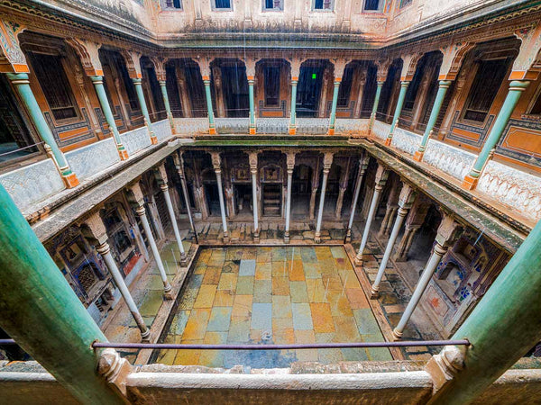Intricate interior design of a Rajasthan haveli with columns and tiled floor.