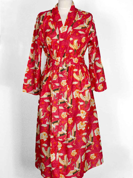 A red kimono-style robe dress with a white, beige, and green crane and floral pattern, displayed on a mannequin against a white background.