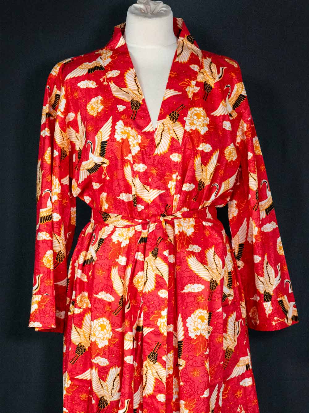 Red robe with bird pattern on a mannequin against a black background