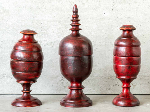 Three red wooden tkka boxes on a neutral background