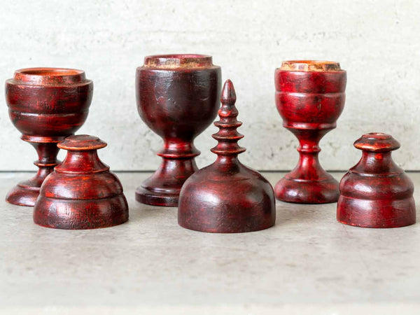 Three red wooden tkka boxes of varying sizes on a light surface with a neutral background