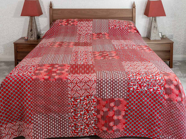 Bed with a red and white patterned quilt in a bedroom setting.