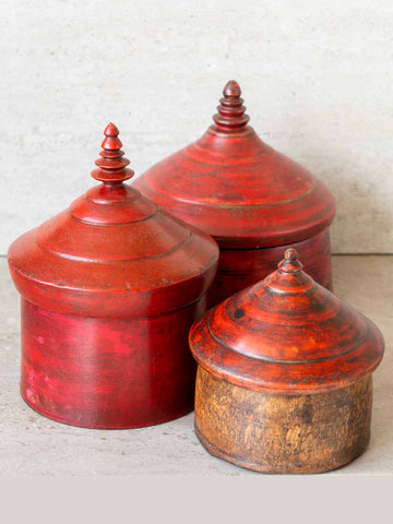 Three red wooden containers with lids on a light background