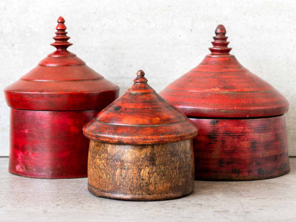 Three wooden containers with red and brown finishes on a light background