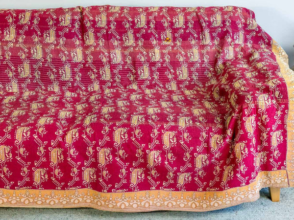 Red and gold patterned fabric draped over a chair