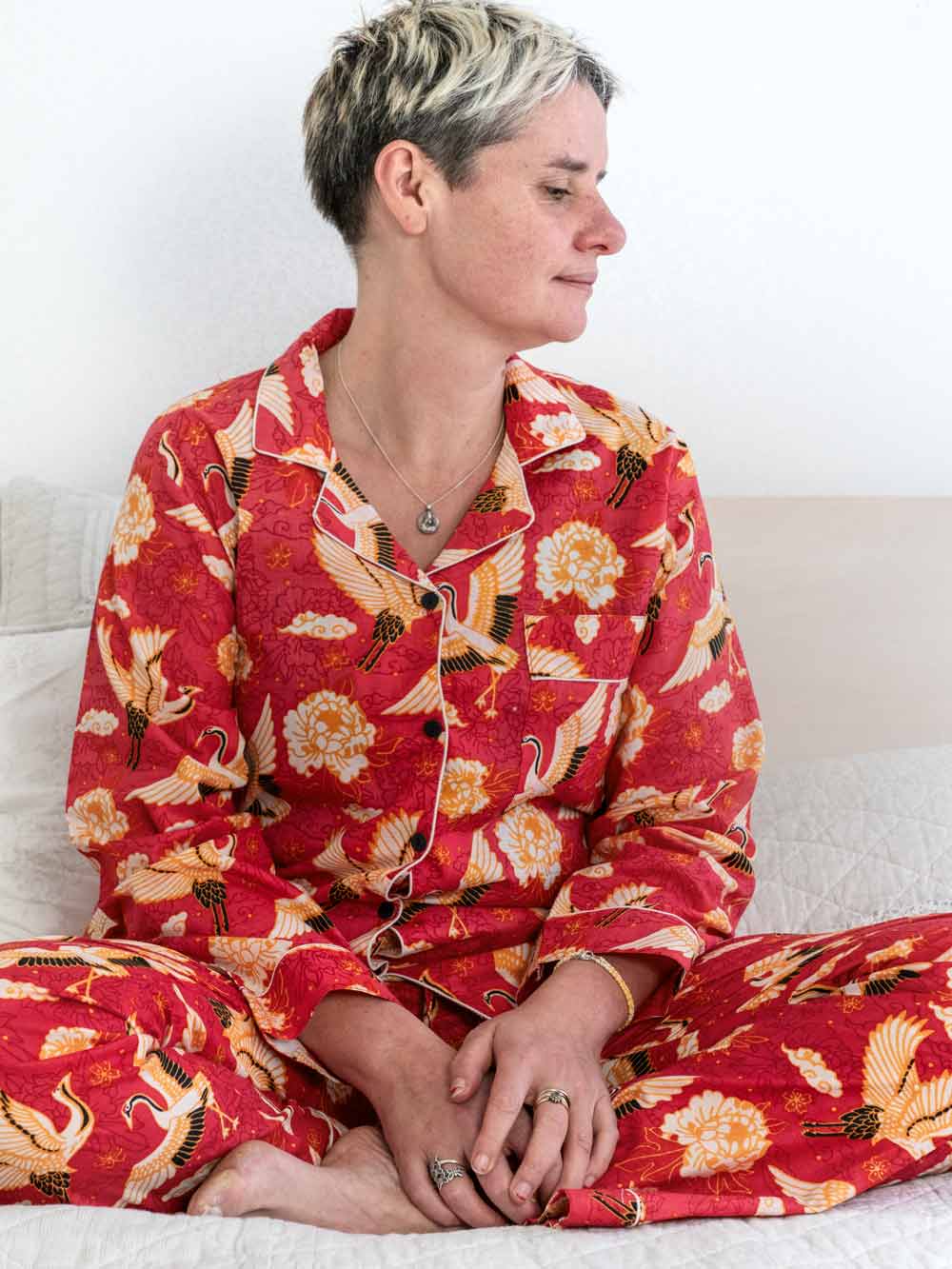 Person wearing a red floral pajama set sitting on a white couch.