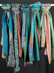 Colorful scarves hanging on a rod against a black background