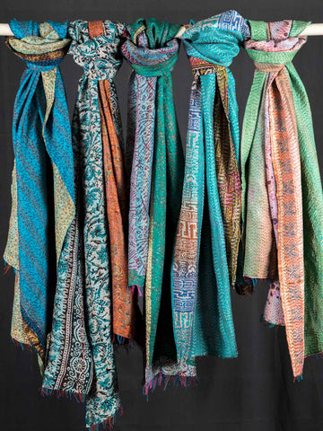 Colorful scarves hanging on a rod against a black background