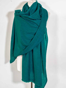 Green scarf draped over a white mannequin on a white background
