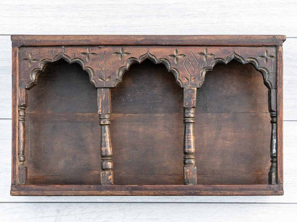 Wooden wall shelf with intricate carvings on a white background
