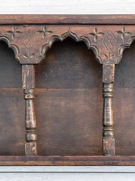 Wooden shelf with intricate carvings on a plain background