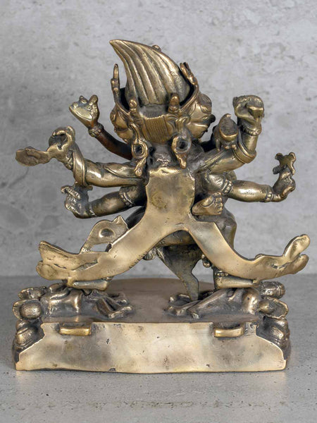 Bronze statue with multiple arms and a fierce expression on a gray background