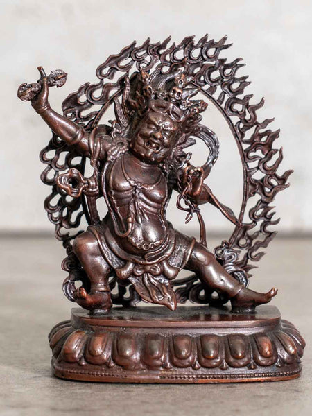 Bronze statue of a deity with intricate design on a plain background