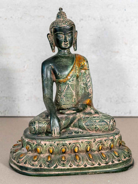 Bronze Buddha statue with green patina on a textured surface