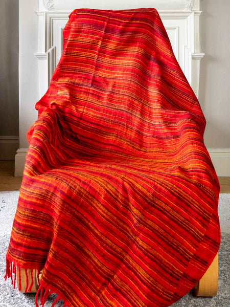 Red striped blanket draped over a wooden chair indoors.