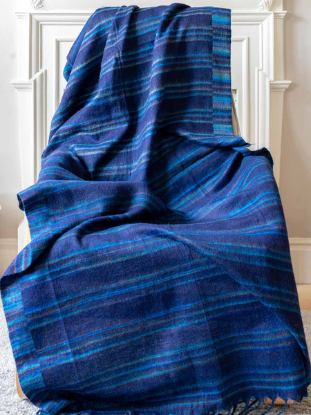 Blue plaid blanket draped over a chair against a white wall.