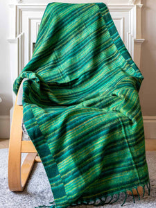 Green plaid blanket draped over a wooden chair indoors.