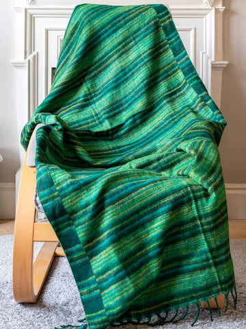 Green plaid blanket draped over a wooden chair indoors.