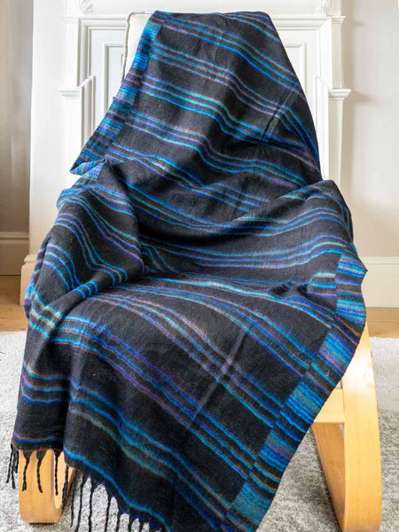 Blue and black plaid blanket draped over a wooden chair indoors.