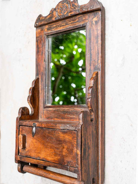 Wooden mirror with decorative frame on a white wall