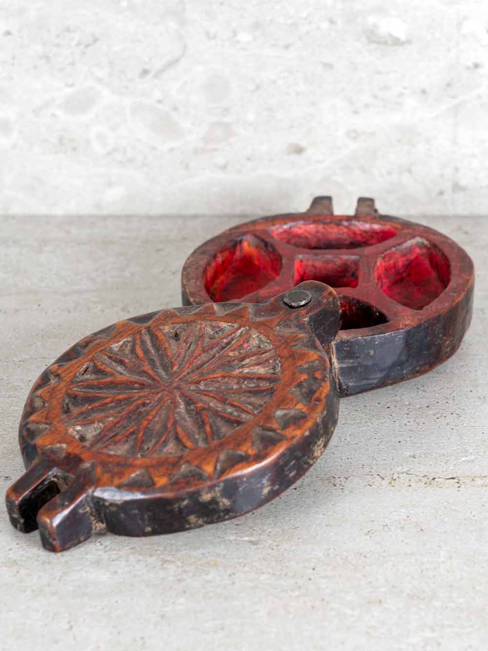 Decorative metal object with red interior on a textured surface