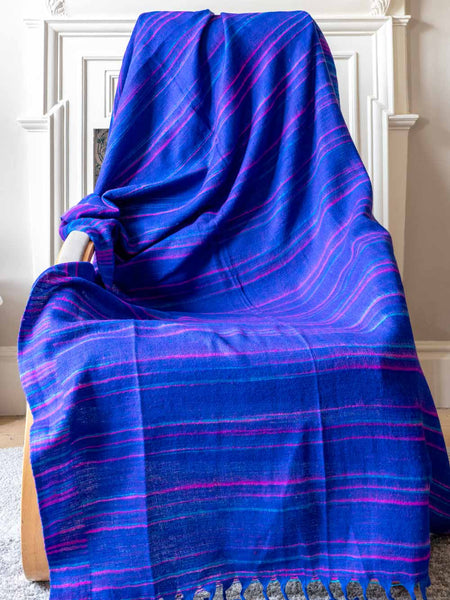 Blue and purple striped fabric draped over a chair against a white wall.