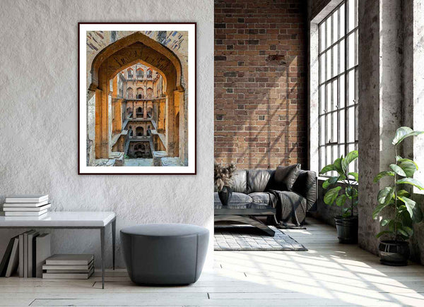 Framed photo of Neemrana stepwell on a wall in a modern living room with a sofa and plants.