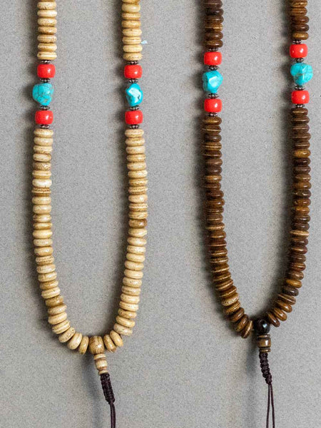 Two beaded necklaces with wooden, turquoise, and red beads on a gray background.