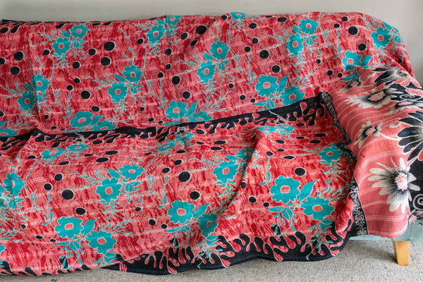 Floral-patterned pink and black blanket draped over a chair.